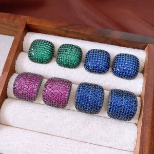 Macro detail of colorful square zircon earrings in a wooden jewelry display case