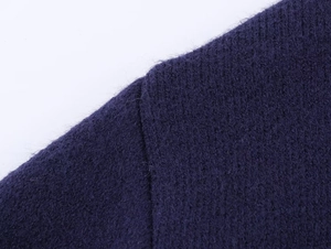 Macro close-up showing the shoulder seam stitching and deep purple knit fabric texture