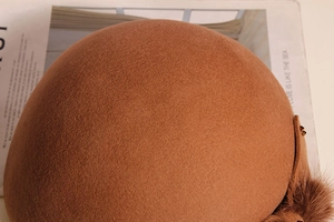 Detailed close-up of wool beret texture with decorative plush ball and elegant finish