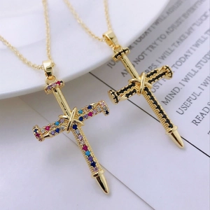 Macro shot of 14K gold cross nail pendants with pavé set colorful and black zircons