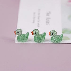 Three glowing green glitter resin ducks in a row for miniature landscape DIY decor