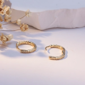 Vintage 925 silver needle gold hoop earrings with embossed patterns on stone background