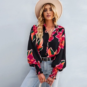 Dettaglio di camicia floreale con polsini elastici e vivaci motivi a fiori rosa e rossi