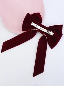 Detail of red velvet bow hair clip showing secure gold metal spring fastener on the back