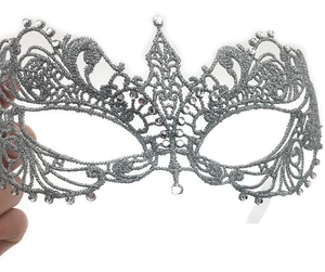 Detail showing hand holding a silver lace masquerade mask with sparkling rhinestones