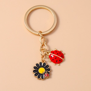Detail view of golden ladybug and black flower charms on a stylish keychain
