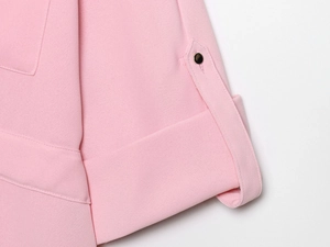 Détail du pantalon large rose montrant le bouton métallique et la qualité des coutures