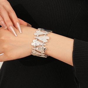 Détail du bracelet à maillons en forme de cœur argenté avec finition martelée sur le poignet
