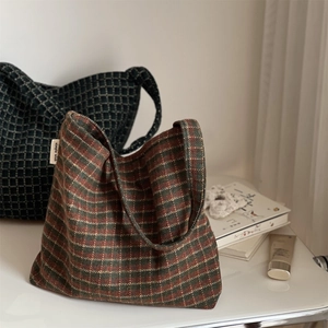 Detail view of red and green plaid woolen tote bags with Simple Wish label on wooden desk