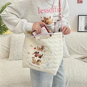 Close-up of cream quilted crossbody bag featuring cute cartoon dog embroidery and daily items