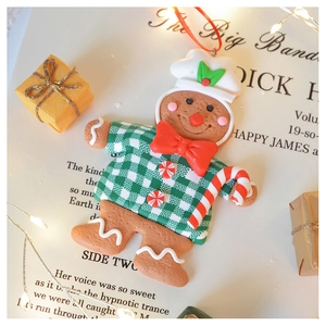 Close-up of clay gingerbread man ornament with red bow on festive background paper