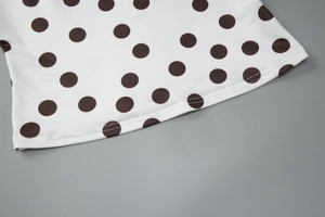 Détail de la couture sur l'ourlet du tissu blanc à pois marrons pour cet ensemble