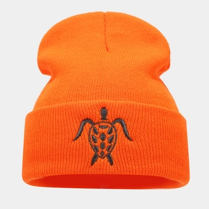 Close-up of bright orange beanie featuring detailed black turtle embroidery on the cuff