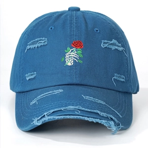 Detail of blue distressed baseball cap with skeleton hand holding rose embroidery