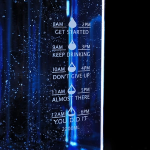 Macro view of 2.2L blue sports bottle with time markers and water droplets on surface
