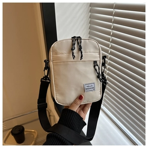 Close-up of beige nylon crossbody bag with Hello Weekend label and black adjustable strap