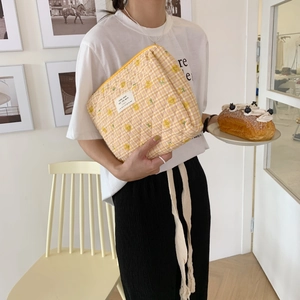 Yellow and white checkered quilted cotton pouch with zipper held by a model