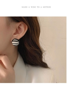 Close-up of a model wearing circular black and white checkered earrings in a retro style