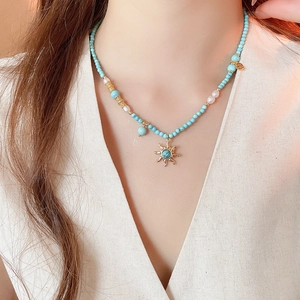 Détail du collier pendentif soleil avec perles turquoise et perles d'eau douce