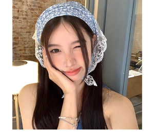 Detail view of blue floral headscarf featuring delicate white lace trim and patterns
