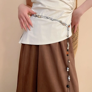 Detailed macro view of leather bead belt with marble and metallic silver charms