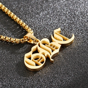 Close-up of golden stainless steel BABE pendant on box chain over black textured background