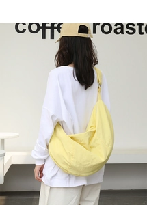Vista posteriore della grande borsa a mezzaluna in nylon giallo indossata dal modello