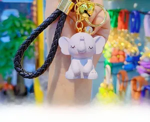 Detail of lavender elephant keychain with golden crown, woven strap, bell and pearl ornament