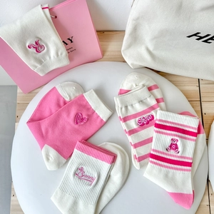 Close-up of pink striped crew socks with cute bear embroidery and heart motifs