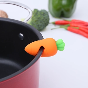 Carrot shaped silicone pot lid lifter and steam releaser on a red cooking pot