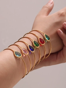 Close-up of six gold-plated bangles with colorful pear-cut Czech glass stones on a wrist