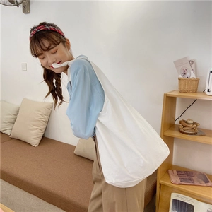 Detailed view of a white canvas tote bag worn by a model in a cozy indoor setting
