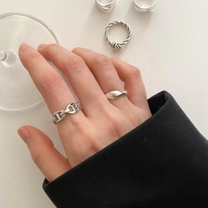 Detail of S925 silver knot and chain rings on fingers with a minimalist aesthetic