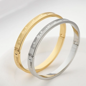 Vista macro di bracciali in acciaio al titanio oro e argento con stelle e trama a griglia