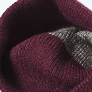 Close-up of a maroon and grey color-block knitted beanie showing thick wool texture