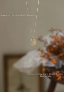 Detailed shot of two-tone oval pendant with moon and star design on a gold chain