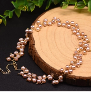 Close-up of pink freshwater pearl necklace with gold wire on a wooden display