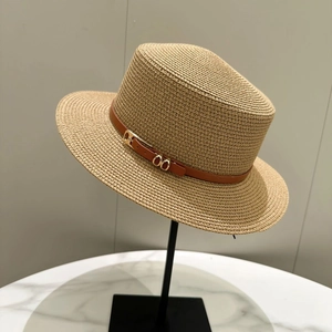 Classic straw sun hat with brown leather band and gold buckle on a marble surface