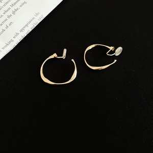 Detailed view of golden twisted hoop earrings with clip-on backs for unpierced ears