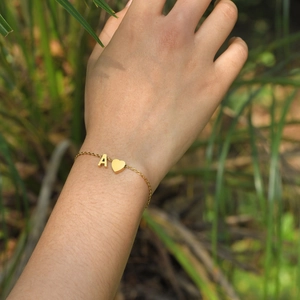 Gold stainless steel heart bracelet with letter A pendant worn on wrist in nature