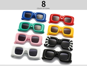Flat lay of futuristic thick-frame sunglasses in eight vibrant colors with soft shadows