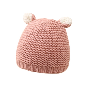 Winter knit baby hat with cute white pompom ears in soft pink crochet style