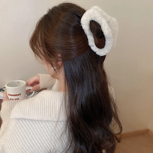 Close-up of white plush cloud hair claw clip on brunette hair for autumn winter