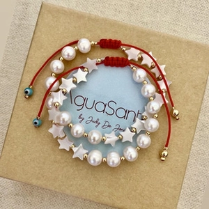 Detail of red cord bracelets with pearls, star shell beads and evil eye charm in a gift box