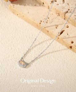 Close-up of champagne moissanite pendant on silver chain with stone background