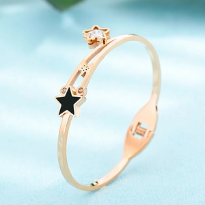 Detailed side view of rose gold bangle with black and sparkling crystal star charms