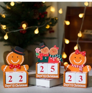 Close-up of three wooden gingerbread man countdown calendars with red and green Christmas decor