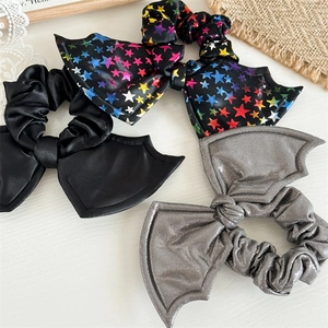 Detailed view of Halloween bat wing scrunchies in black, silver, and star satin fabric