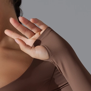 Dettaglio delle maniche del top yoga marrone scuro con pratici fori per i pollici