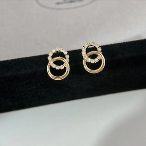 Detail of interlocking gold hoop earrings with sparkling crystal pavé on black velvet